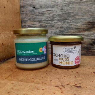 Schoko Nuss im Honig und Blütenzauber Honig im Paket vor einem Bienenkasten